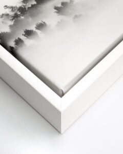 Close up of the corner of a black and white image printed on canvas with a white float frame