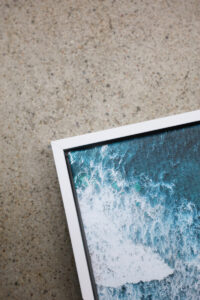 Corner of a white float framed canvas print of the beach