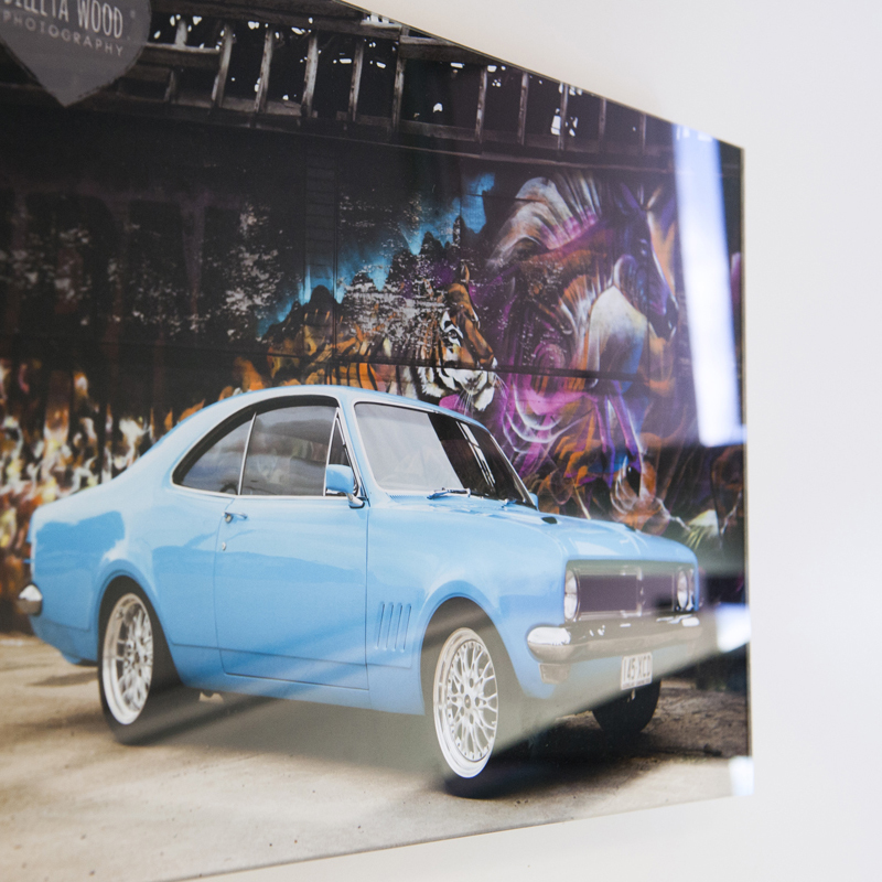 Acrylic Print of a blue retro car hanging on a white wall