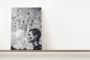 Stretched canvas print on a floating shelf of a black and white double exposure image of a woman and flowers
