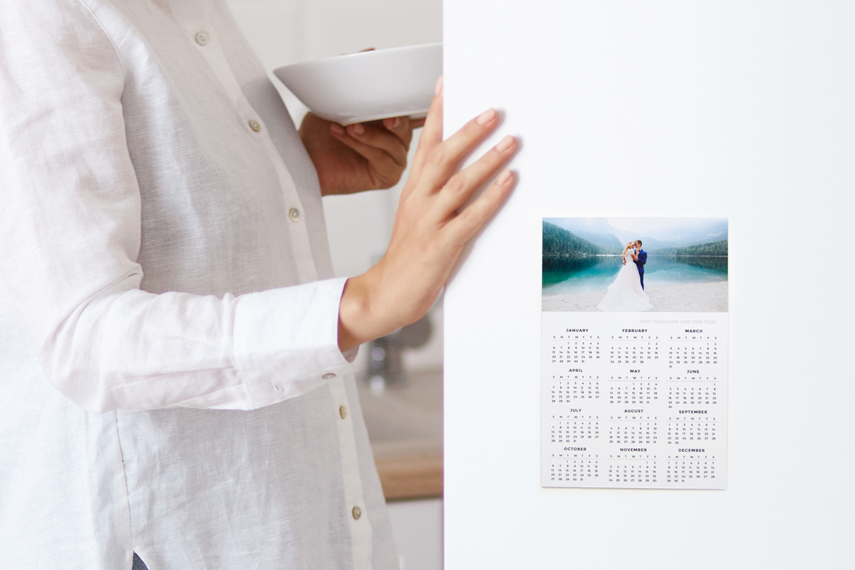 Opening a fridge door with photo magnet calendar and image of bride and groom