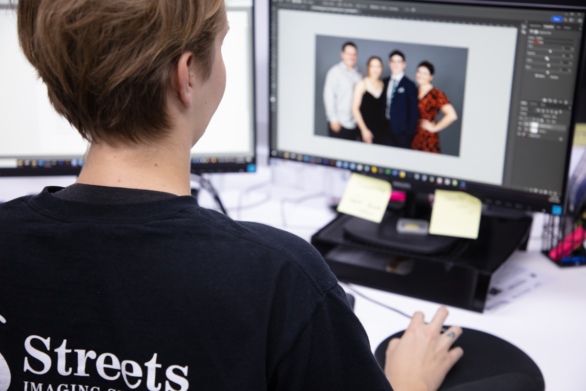 Lab staff sitting at a computer performing photo editing and restoration