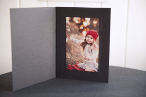 Black photo folder standing up with a lustre print of a girl inside