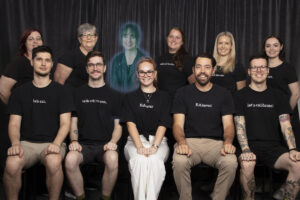 Staff photo of everyone sitting in two rows one of the remote working staff has jedi ghost glow