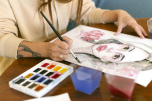 Woman painting an illustrative portrait with watercolours